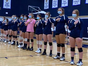 The Varsity Volleyball team lines up for the national anthem in masks prior to their game vs. district rival Second Baptist