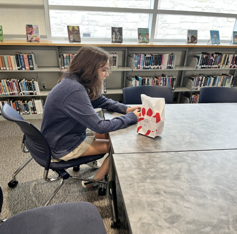 Junior Audrey Hochglaube sits in the library waiting to enjoy her Chick-fil-A during snack.