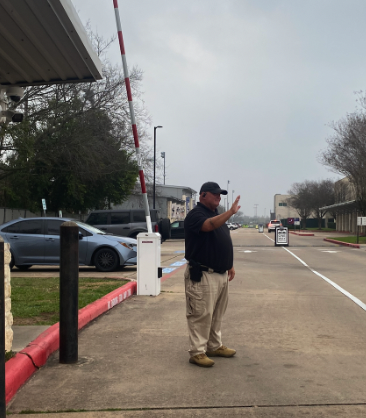 School Safety Assistant, Thomas Peterson, greeting cars as they drive into campus. 